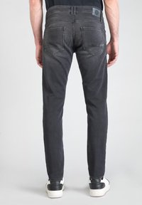 Jeans gris oscuro con un ajuste slim, cinco bolsillos y un sutil acabado deslavado. Complementados con una etiqueta negra en la cinturilla.