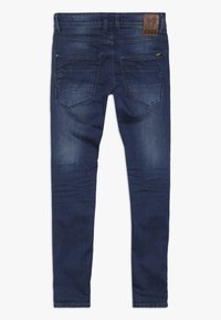 Úzké džíny v tmavě modrém denimovém materiálu s mírným vyšisováním. Obsahují dvě zadní kapsy a koženou značkovou nášivku na pase.