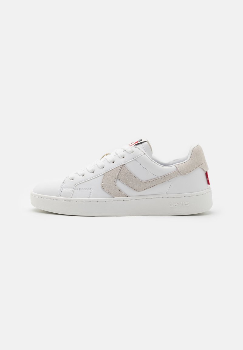 Baskets basses blanches avec accents en daim beige, lacets blancs et semelle épaisse, présentées de côté externe sur un fond uni.