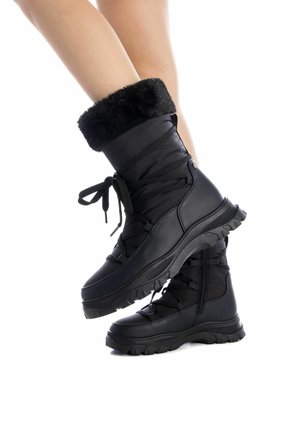 Botas negras aisladas con puños de piel sintética, que cuentan con un diseño de cordones y suela de goma texturizada para mayor tracción. Material resistente al agua.