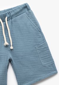 Blaue Baumwollshorts mit einem elastischen Bund, beigem Kordelzug und Seitentasche. Die Textur ist leicht gerippt.