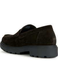 Brun mockaskinn slip-on sko med en strukturerad yta, rund tå och tjock svart gummisula med ett mönster av spår.