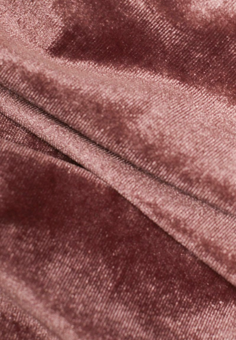 Eingeklemmter Samtstoff in einem gedämpften Mauve-Ton, der eine weiche, glatte Textur mit einem leichten Schimmer und subtilen Farbvariationen aufweist.