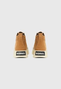 Brown suede high-top sneakers with a contrasting cream rubber sole, featuring black logo accents on the heels.