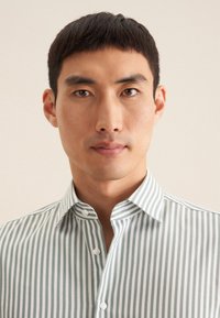 Camicia con colletto a righe verticali verdi e bianche, realizzata in un tessuto leggero, con chiusura a bottoni e una trama liscia.