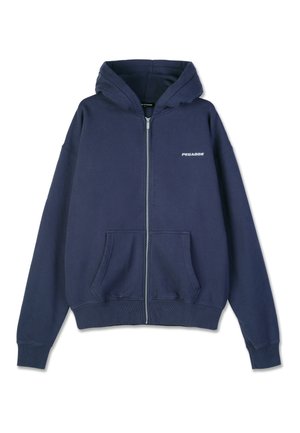 Sudadera con cremallera azul marino que incluye una capucha, bolsillos frontales, puños acanalados y un pequeño logo "PEGADOR" en el lado izquierdo del pecho. Textura de material suave.