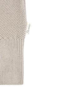 Beige knitted fabric with a textured pattern on top and ribbed knit at the bottom, featuring a small fabric tag with "Sterntaler" text.