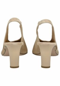 Zapatos de tacón slingback de ante beige con punta redonda, tacón bajo y correa en el tobillo. Textura suave con detalles mínimos en el cuerpo del zapato.