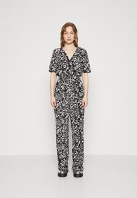 Combinaison à imprimé floral noir et blanc avec manches courtes, décolleté en V, taille cintrée et coupe droite. Tissu doux et design décontracté.