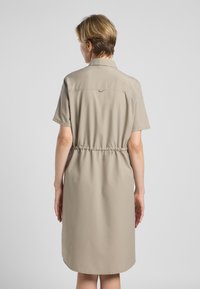 Beige korte mouwen jurk met een kraaghalslijn. Kenmerkt een elastische taille en een afgeronde zoom. Gemaakt van een lichtgewicht, gladde stof.