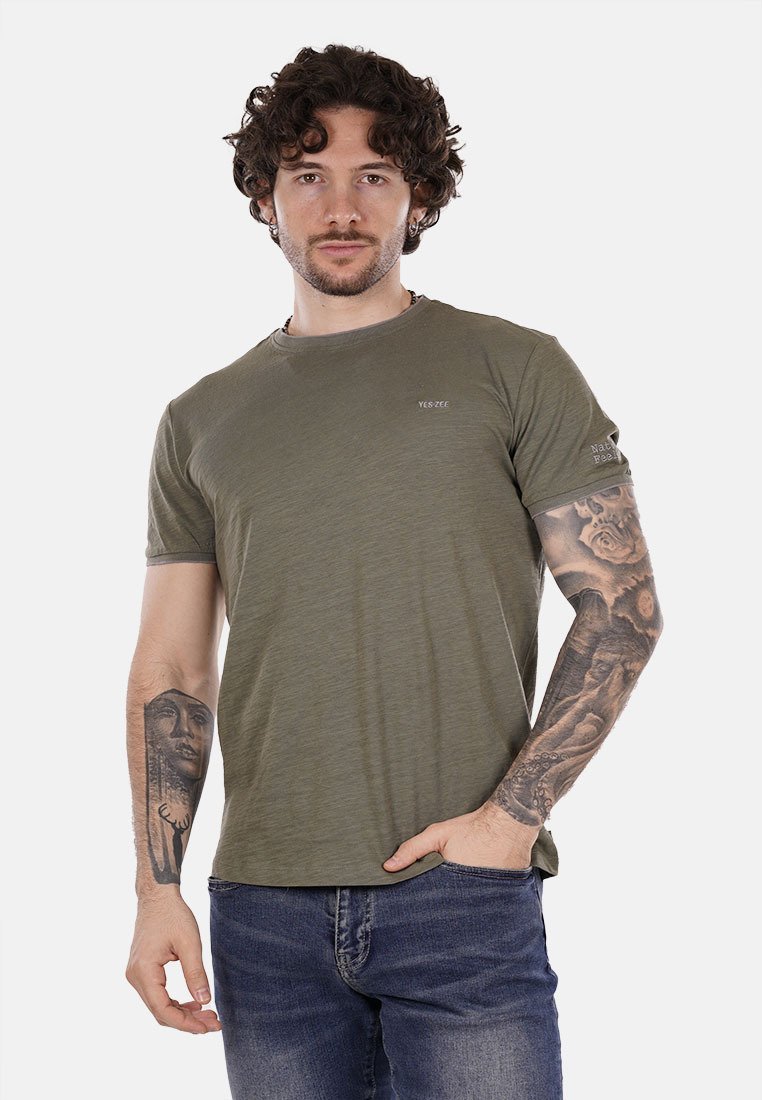 T-shirt crew neck verde oliva, maniche corte, con un logo discreto sul petto e sulla manica. Il tessuto ha un aspetto morbido e testurizzato.