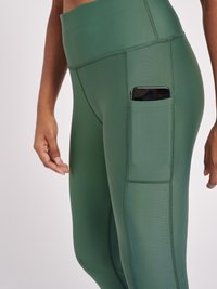 Hoogtaille groene legging gemaakt van rekbaar materiaal, met een zijzak voor een telefoon en platte naden voor comfort.