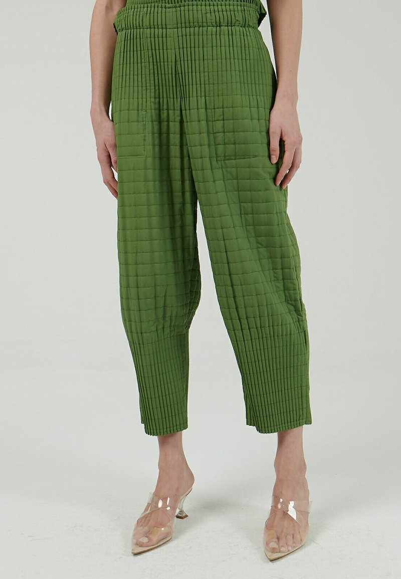Gequilte groene broek met een gestructureerd oppervlak, voorzien van een elastische tailleband en wijde benen. Gestyled met doorzichtige hakken.