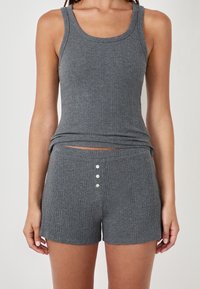 Conjunto de top de tirantes gris acanalado y pantalones cortos, con un escote redondeado y detalle de tres botones en los pantalones. Textura suave y diseño ajustado.