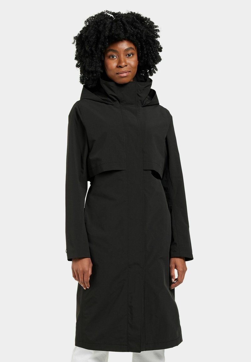 Manteau de pluie noir avec capuche, au design court et à manches longues. Tissu lisse et imperméable avec un minimum de détails.