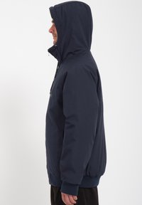 Marineblauwe hoodie-jack met een ritssluiting, elastische manchetten en een geribde zoom. Beschikt over een gladde, waterafstotende stof en zijzakken.
