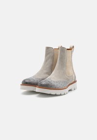 Stivali alla caviglia in suede grigio con punta in stile brogue, pannelli laterali elasticizzati beige e suola in gomma bianca con battistrada testurizzato.