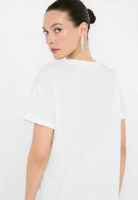 T-shirt bianco in cotone con maniche corte e scollatura rotonda. Presenta una texture liscia e una vestibilità comoda.