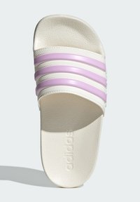 White slide sandal with three purple stripes across the top. Made of textured material, featuring a raised logo on the footbed.