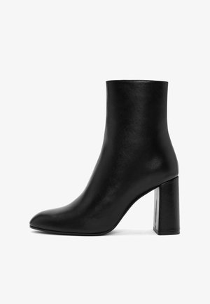 Bottine en cuir noir avec un bout pointu et un talon épais haut. Texture lisse avec un design minimaliste et sans matériel ou accents visibles.