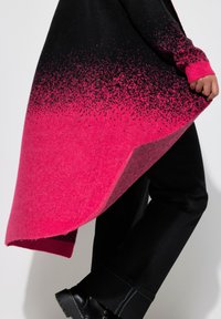 Cardigan en tricot dégradé noir et rose avec des longues manches et un ourlet asymétrique. Texture douce avec une finition duveteuse et un design moderne.
