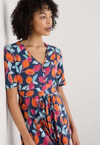 Navy dress featuring a vibrant floral pattern in orange, pink, and teal, with short sleeves and a V-neckline. Soft, textured fabric.
