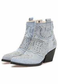 Stivali in denim alla caviglia con punta affusolata, di colore azzurro chiaro, adornati con borchie d'argento e tacco a zeppa. Presentano cuciture decorative.
