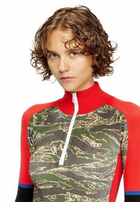 Maglia protettiva con cerniera caratterizzata da un motivo mimetico nei toni del verde, crema e nero, con accenti rossi e blu sulle spalle e sul collo. Texture a coste.