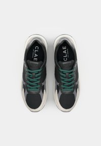 Black athletic shoes with teal laces, suede and mesh upper, and a thick grey rubber sole. Features branding on the tongue.