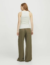 Hvid ribbet tanktop parret med olivengrønne brede bukser med sidelommer og en blød struktur. Modellen ses fra ryggen.
