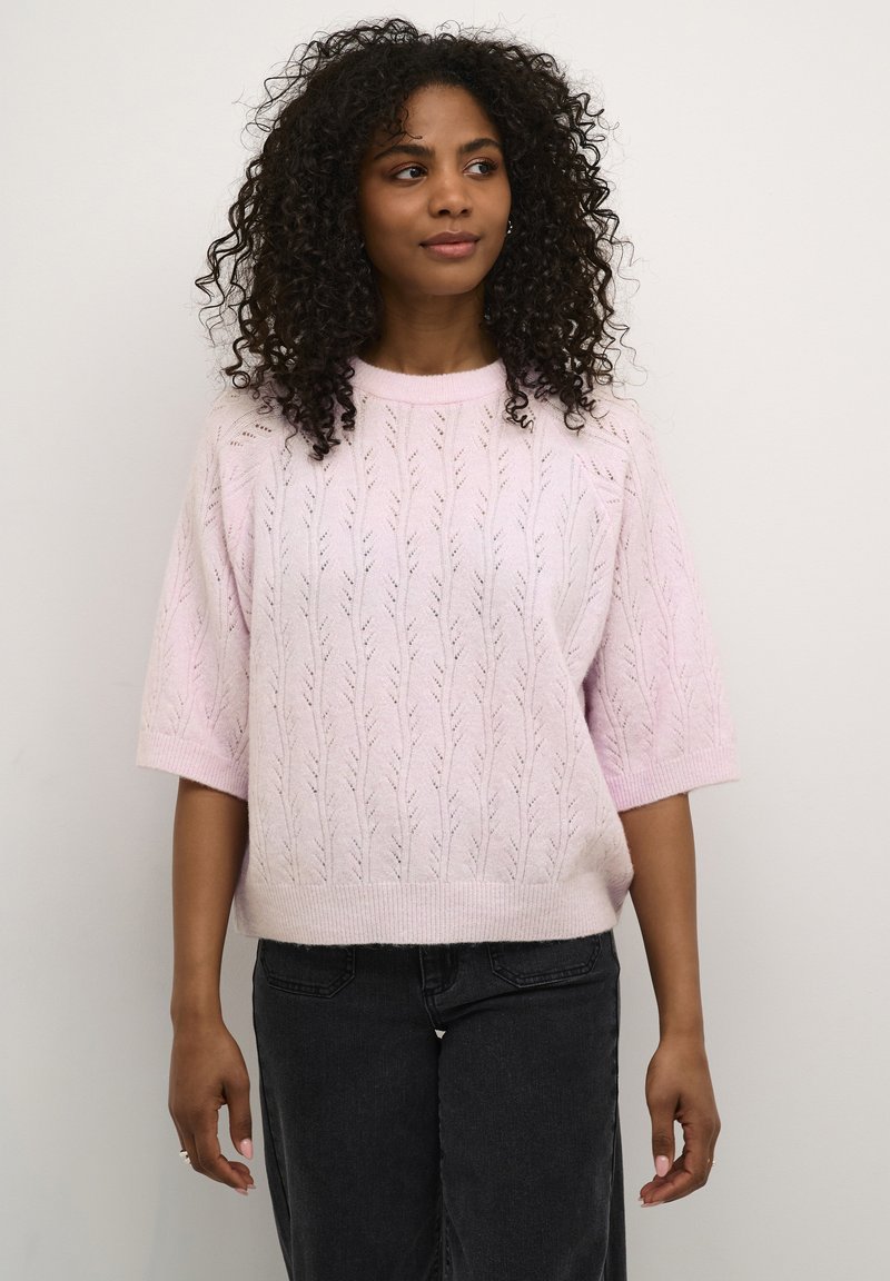 Lichtroze gebreid sweater met een bladerenpatroon, korte mouwen en een ronde halslijn, gecombineerd met donkerdenim broek.