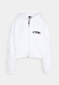 Hoodie court blanc en matériau pelucheux, avec une fermeture éclair, une capuche à cordon et un patch logo noir sur la poitrine.