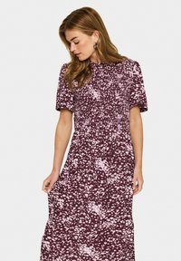 Rochie maxi de culoare burgundă cu un model abstract alb, cu mâneci scurte și elastic pe corp, având buzunare laterale.