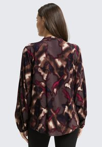 Long-sleeve blouse in dark purple with abstract patterns in shades of burgundy, brown, and cream; soft, flowing fabric with gathered cuffs.