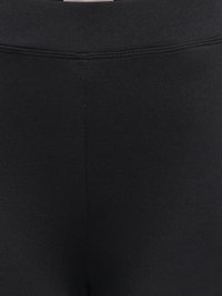 Close-up of black stretchy fabric leggings showing the elastic waistband and center seam stitching.
