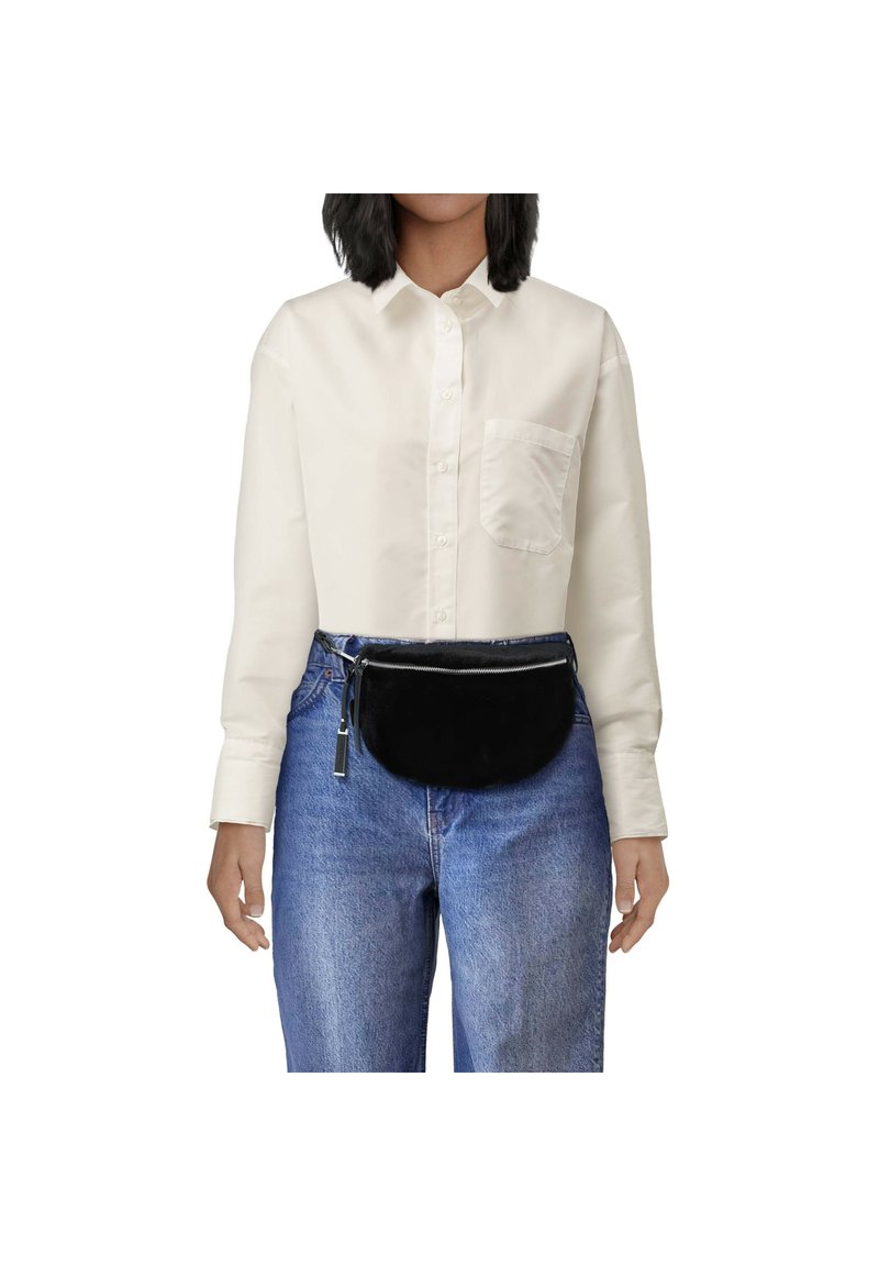 Schwarze Stoffgürteltasche mit Reißverschluss, getragen über einem hellen Button-Up-Hemd und blauen Jeans. Weiche Textur und abgerundete Form.