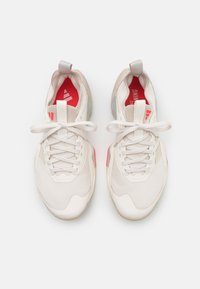 White athletic shoes with mesh and synthetic materials, featuring pink accents, flat laces, and a padded tongue, shown from above.
