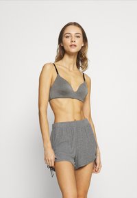 Szürke bralette fekete állítható pántokkal, sima textúrával és V-nyakú kialakítással. Szürke, rugalmas derékú sorttal párosítva.