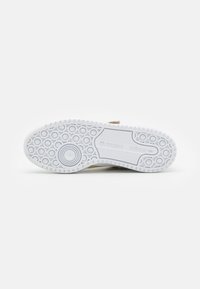 Light beige sneaker with a white textured rubber sole featuring circular patterns and an adidas logo near the heel.