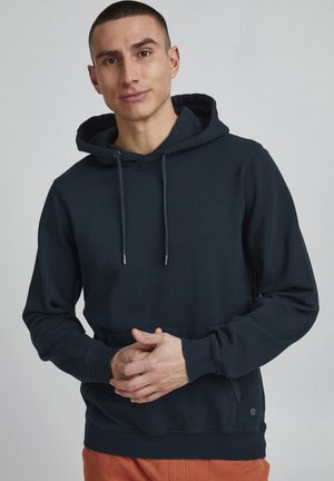 Dunkelblaues Kapuzenshirt aus Baumwolle mit einer Kängurutasche, Kordelzugkapuze und gerippten Bündchen. Minimale Markenkennzeichnung am Saum.