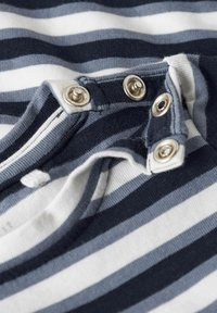 Gestreepte katoenen stof in donkerblauw, lichtblauw en wit. Bevat metalen drukknoopjes langs de halslijn voor sluiting. Zachte textuur.