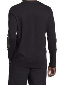 Zwart shirt met lange mouwen gemaakt van katoen, met groene accenten op de mouwen en een ronde halslijn. Gladde textuur en reguliere pasvorm.