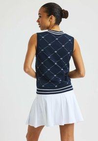 Golftröja i västmodell i marinblått med vita accenter, med ett broderat diamantmönster, ärmlös design och ribbad krage.