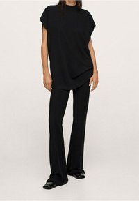 Sort, løstsiddende top med korte ærmer, der er parret med sorte, brede bukser. Stoffet ser glat ud med et minimalistisk design.