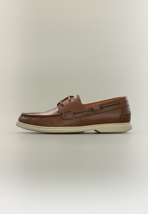 Brązowy skórzany but typu boat shoe z beżową gumową podeszwą i sznurowaniem, widok z boku na neutralnym tle.