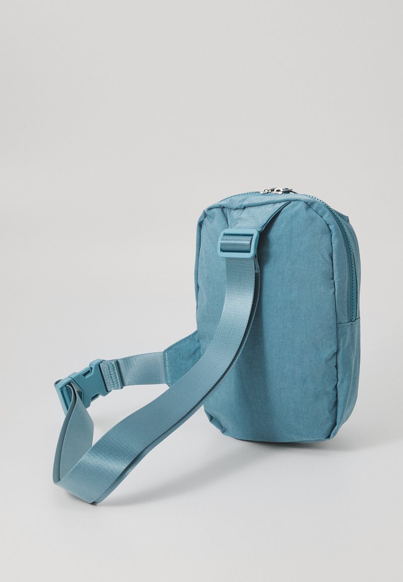 Bolso de hombro de tela verde azulado con cierre de cremallera, correa ajustable, forma rectangular y textura suave. Adecuado para uso casual.