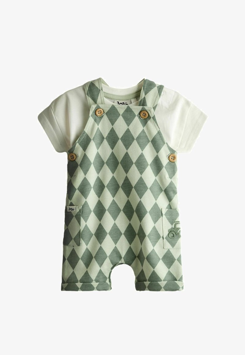 Bērnu apģērbs ar baltu īsroku kreklu un zaļām kombinezonām ar dimanta rakstu, kurās ir koka pogas un mazas priekšējās kabatas.