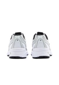 Weiße und schwarze Sportschuhe mit strukturiertem Obermaterial, einer gedämpften Sohle und reflektierenden Akzenten an den Seiten und am Rücken.