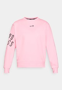 Sweatshirt rose avec un col rond, des poignets et un ourlet côtelés. Présente un petit logo noir sur la poitrine et un texte en gras sur la manche gauche.