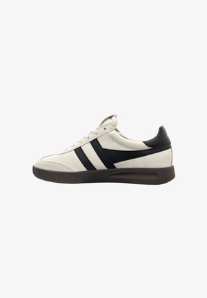 Sneaker en cuir blanc avec des accents et des rayures noires, présentant un capuchon de coque texturé et une semelle en caoutchouc. Design à lacets et talon rembourré.